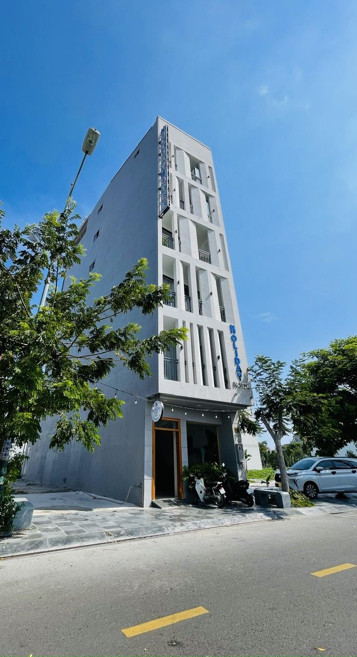A modern hotel with a vertical facade, balconies, and a sign indicating it is a hotel.