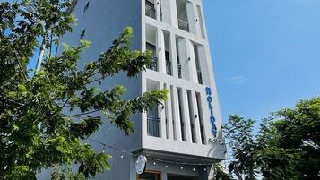 A modern hotel with a vertical facade, balconies, and a sign indicating it is a hotel.