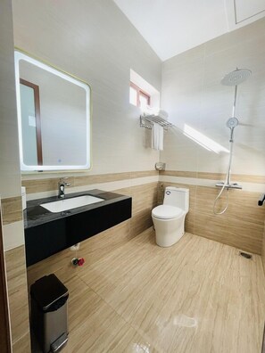 Ein modernes Badezimmer mit großem Spiegel, Waschbecken, Toilette und Dusche.