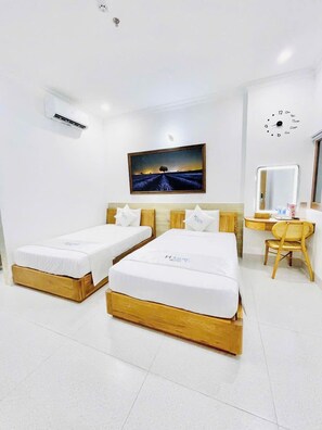 Ein Hotelzimmer mit zwei Einzelbetten, einem Holzkopfteil, einer Wanduhr, einem Gemälde und einem Schreibtisch mit Stuhl.
