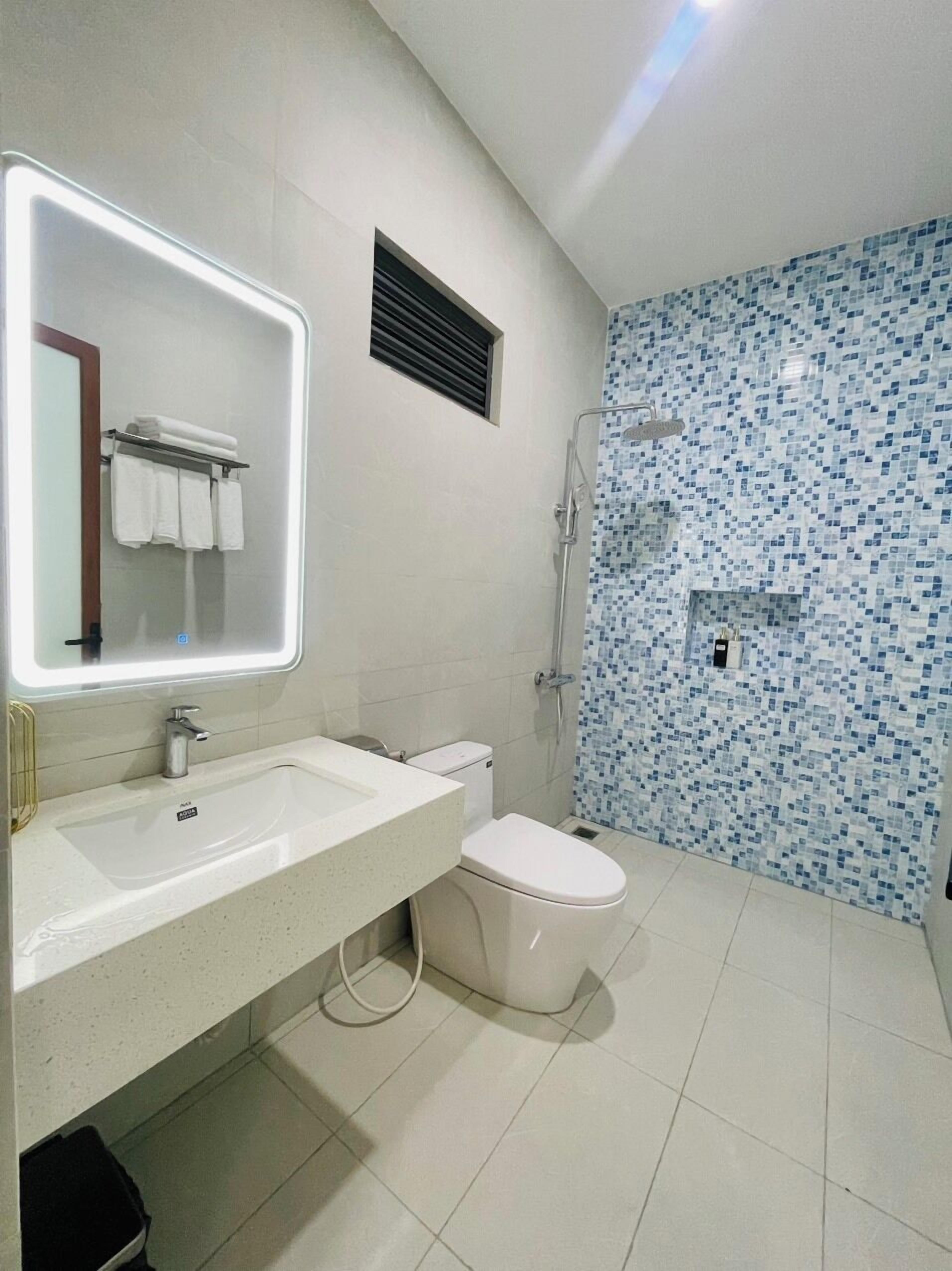 Une salle de bain moderne avec un lavabo blanc, des toilettes et une douche.