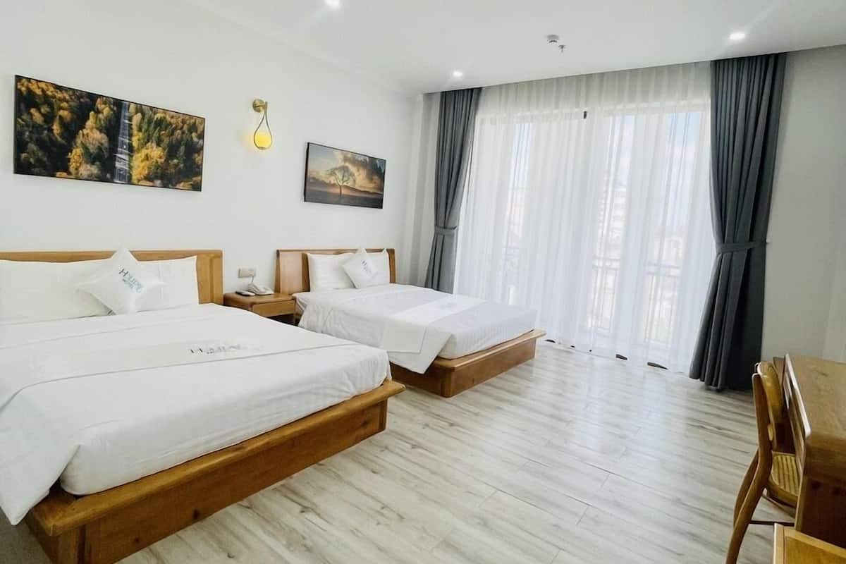 Una habitación de hotel con dos camas, piso de madera, un escritorio y una silla.