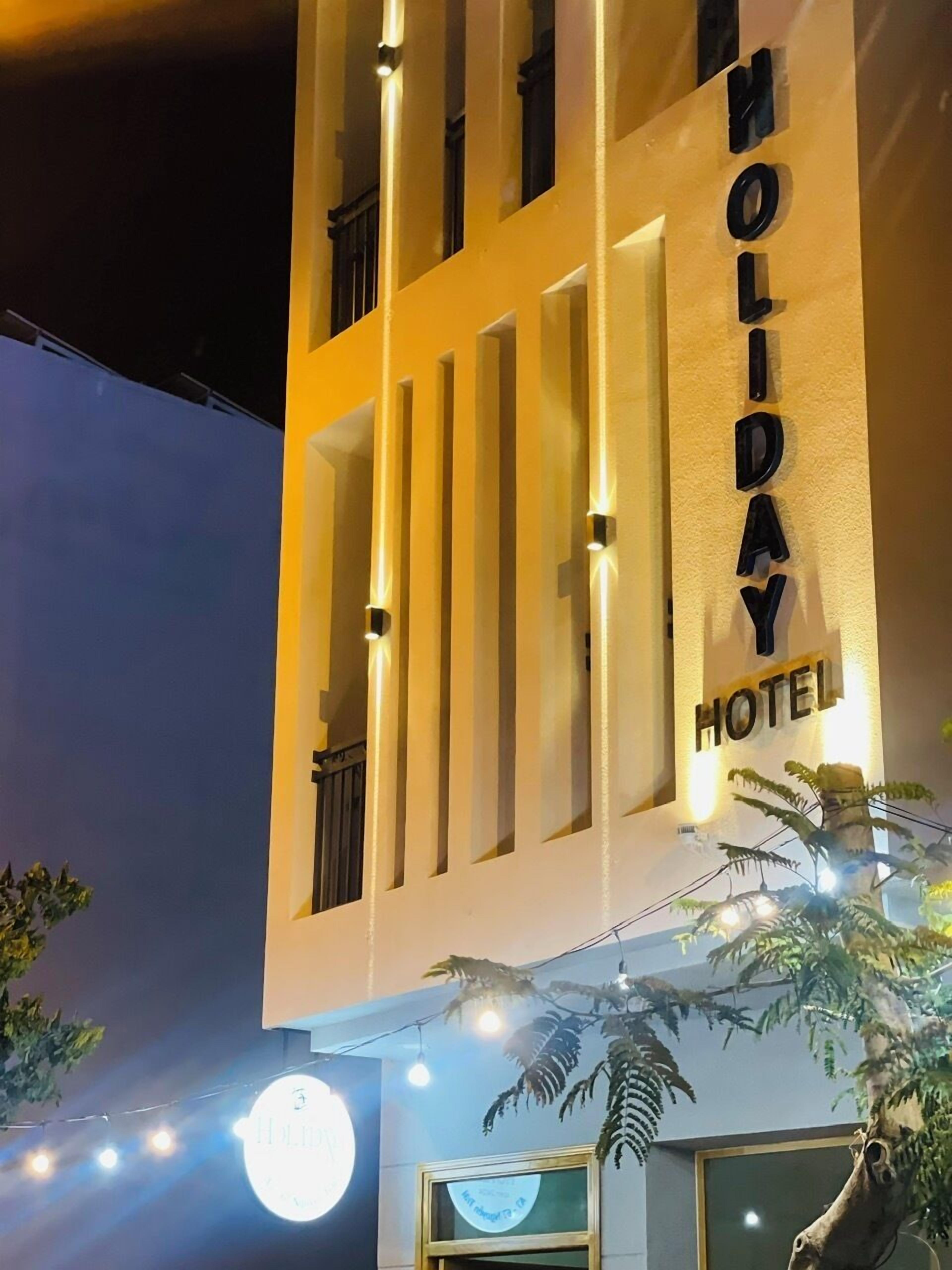 A building with a sign reading 'HOLIDAY HOTEL' and a circular sign with the word 'HOLIDAY' on it.