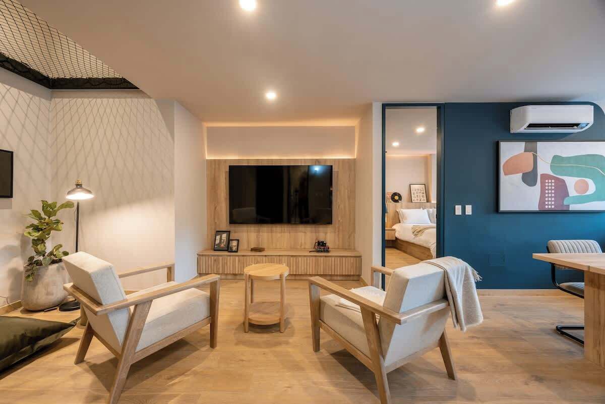 Ein modernes Wohnzimmer mit großem Fernseher, Holzmöbeln und einer blauen Akzentwand.
