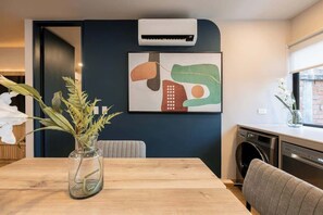 Una cocina moderna con aire acondicionado integrado, una mesa de comedor con un jarrón de flores y un cuadro abstracto colgado en la pared.