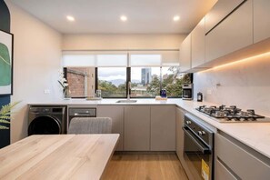 Una cocina moderna con lavadora integrada, un ventanal y vistas de la ciudad.