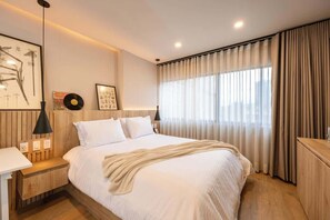 A modern bedroom with a large bed, bedside tables, a desk, and a window with curtains. - Digital Nomad Paradise 2BR Sanctuary with A/C (Medellín)