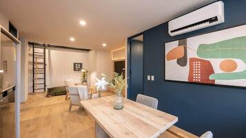 Un interior moderno con una mesa de comedor de madera, un jarrón de flores y un cuadro abstracto grande en la pared.