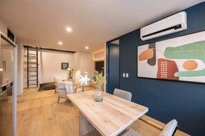 A modern interior with a wooden dining table, a vase of flowers, and a large abstract painting on the wall. - Digital Nomad Paradise 2BR Sanctuary with A/C (Medellín)