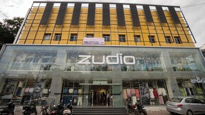 Ein Gebäude mit einer gelben Fassade und einer großen Glasfront, auf der "Zudio" steht.