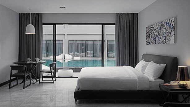 Une chambre d’hôtel moderne avec un grand lit, un bureau et une vue sur une piscine.
