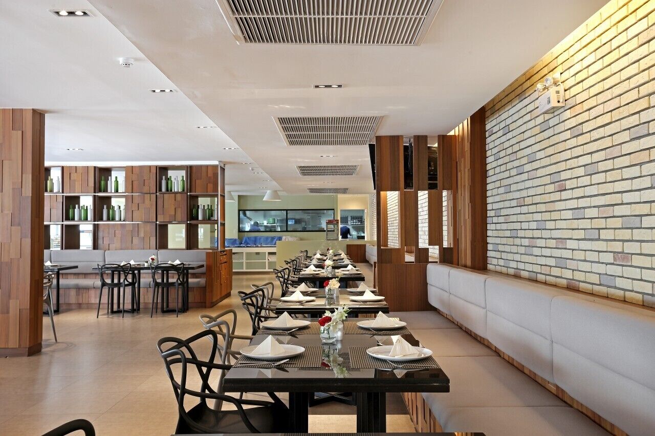 A modern restaurant with long tables, wooden accents, and brick walls.