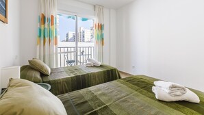 A hotel room with two beds, a balcony, and a view of buildings. - A&N Marisol (Torre del Mar)