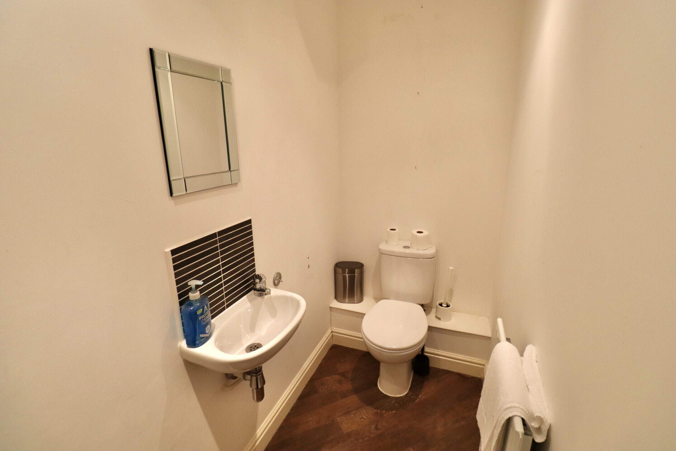 Ein kleines Badezimmer mit Waschbecken, Toilette und Spiegel.