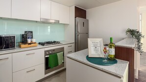 A modern kitchen with white cabinets, stainless steel appliances, a coffee machine, and a welcome sign.