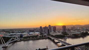 A cityscape with a river, bridges, and high-rise buildings during sunset.