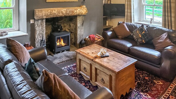 Un salon chaleureux avec une cheminée en pierre, des canapés en cuir et une table basse en bois.