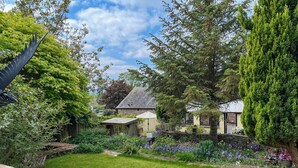 A traditional house surrounded by a well-maintained garden with a variety of plants and flowers.