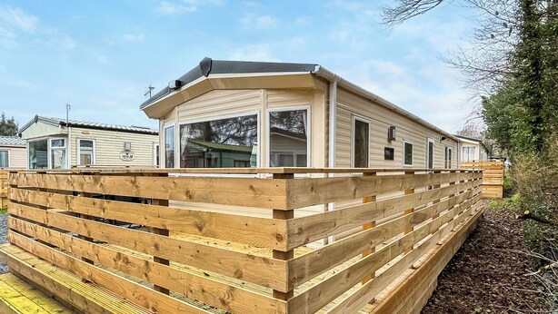Une maison mobile dotée d’une terrasse en bois et d’une grande fenêtre.