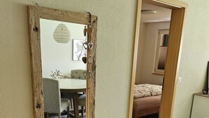 A room with a large mirror, a bench, and a door leading to another room.