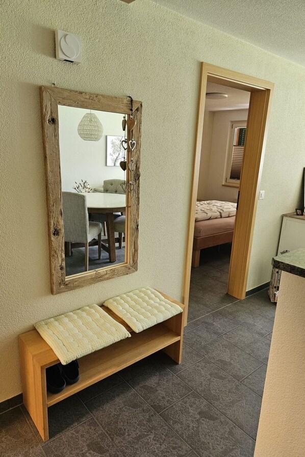 A room with a large mirror, a bench, and a door leading to another room. - Bergecho EG Mitte by Interhome (Lenk)