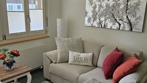 A living room with a sofa, a coffee table, and a painting on the wall.