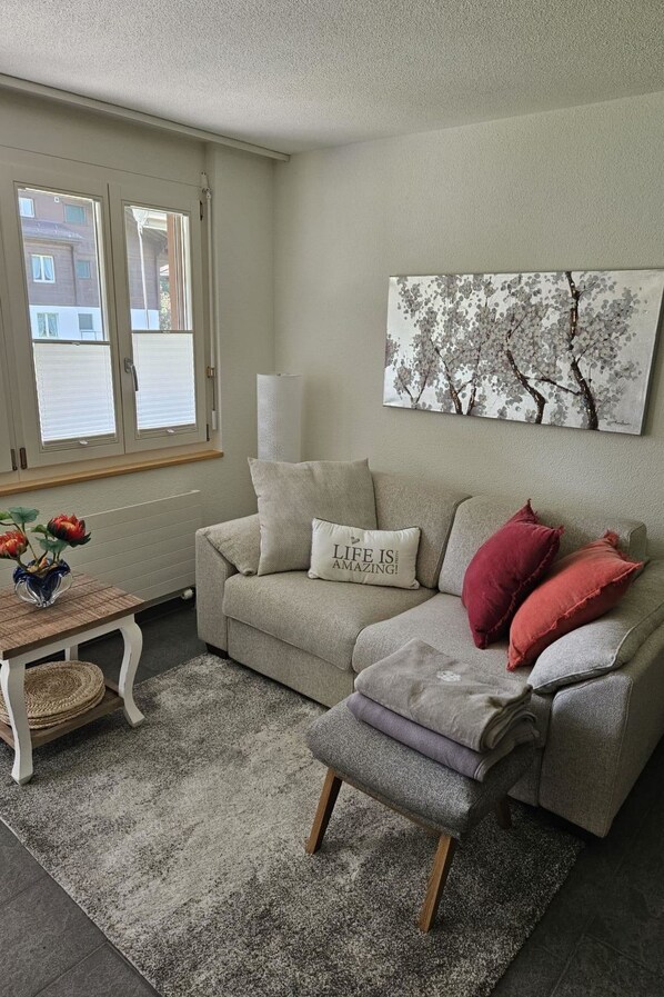 A living room with a sofa, a coffee table, and a painting on the wall.