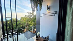 A balcony with a glass floor, a table with a bottle and glass, and a chair. - A303 - 1 Bedroom Serviced Apartment Partial Sea View at Ao Nang Beach (Tambon Ao Nang)