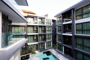Ein modernes, mehrgeschossiges Gebäude mit Balkonen, großen Fenstern und einem zentralen Innenhof mit Pool.