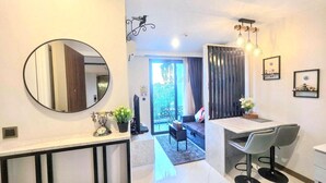 A modern interior with a round mirror, a dining area with a table and chairs, a small seating area with a sofa, and a view through a door to an outdoor space. - A303 - 1 Bedroom Serviced Apartment Partial Sea View at Ao Nang Beach (Tambon Ao Nang)