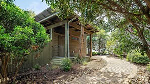 A house with a covered porch, a paved driveway, and surrounding greenery.