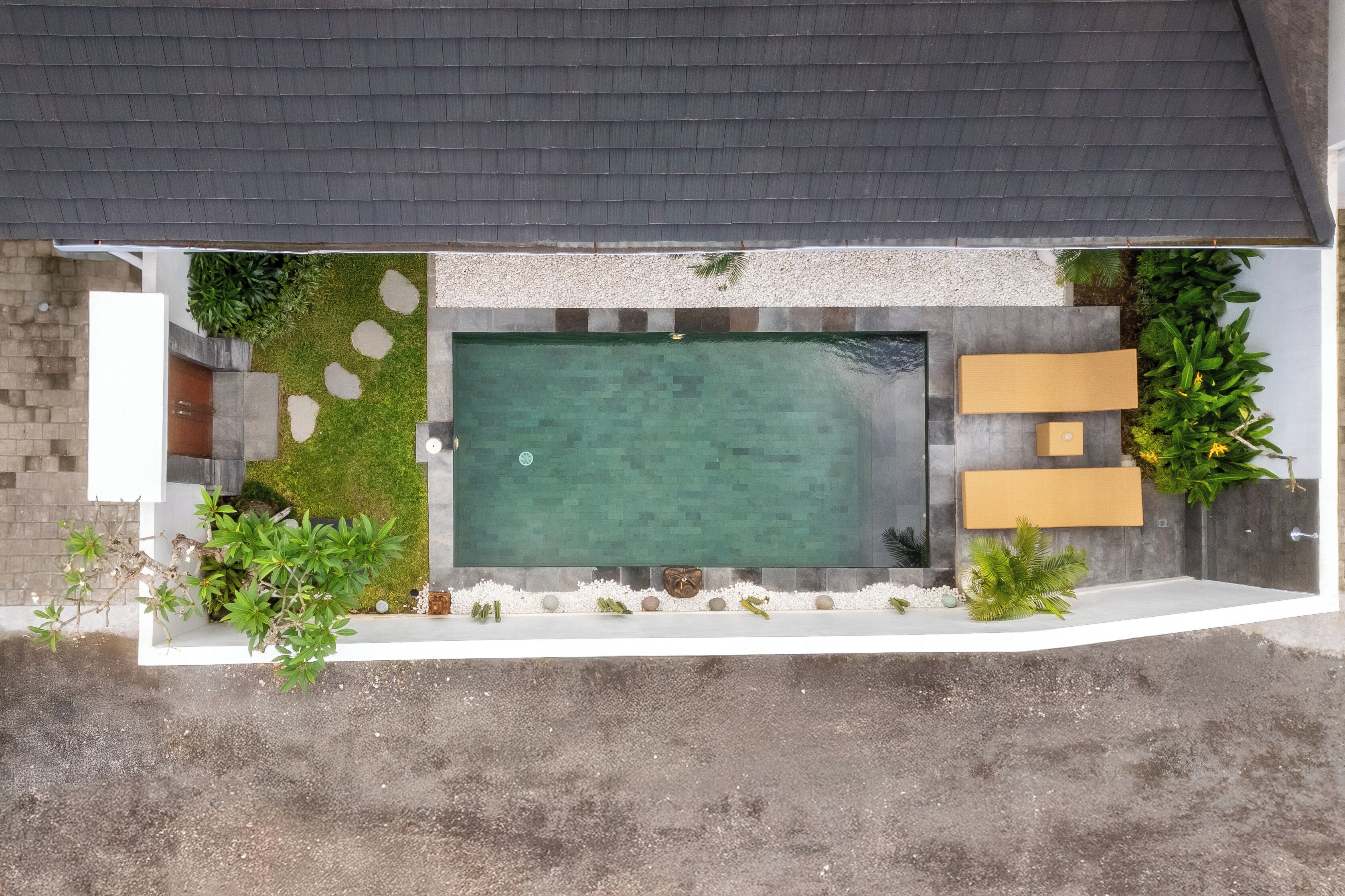 Vue aérienne d’une cour arrière avec une piscine, un espace détente et diverses plantes.