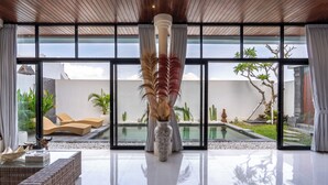 Een modern interieur met een groot raam, een decoratieve vaas en een zwembad buiten.