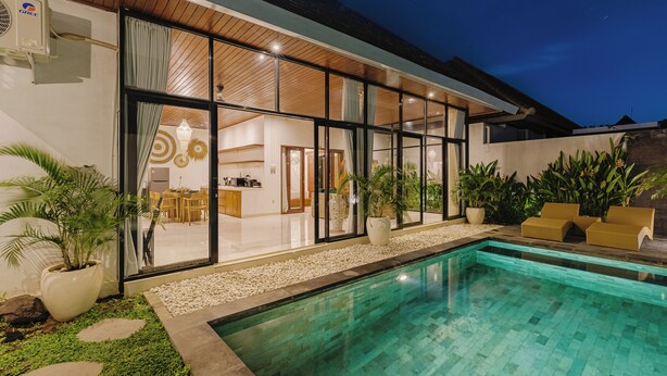Een modern huis met een zwembad, grote ramen en een verzorgde tuin.