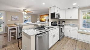 A modern kitchen with white cabinetry, stainless steel appliances, and a granite countertop. - 3BR Guest Escape w/ Pool & Theater (Palm Harbor)