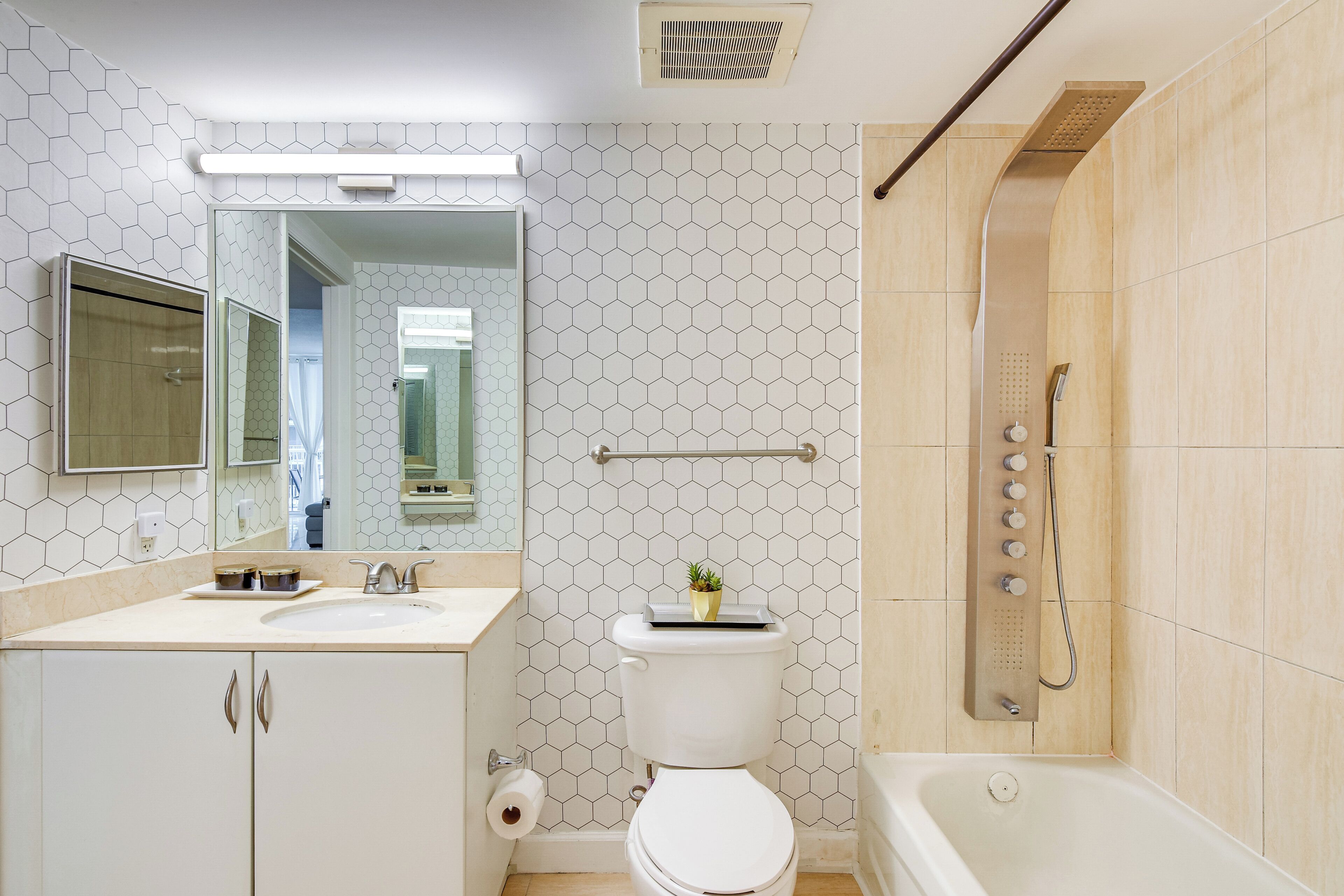 Un bany modern amb un disseny de rajoles hexagonals, un lavabo blanc, un vàter i una zona de dutxa.