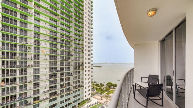 Un immeuble de grande hauteur doté de nombreux balcons, d’un espace piscine et offrant une vue sur l’eau.