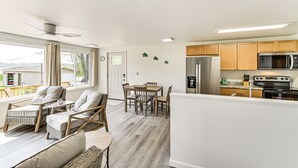 A modern kitchen with wooden cabinets, a refrigerator, a microwave, and a stove. There is a dining area with a table and chairs. - Deck, Dock & Hot Tub: Lakeside Retreat in Michigan (Hartford)