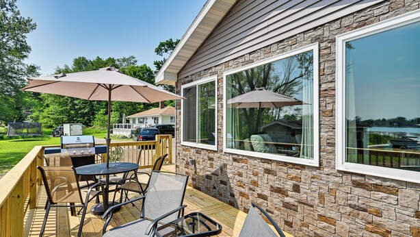 An outdoor patio with a wooden deck, metal chairs, and a grill. - Deck, Dock & Hot Tub: Lakeside Retreat in Michigan (Hartford)