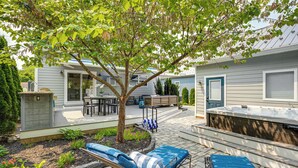 A backyard with a hot tub, two lounge chairs, a wooden deck, and a small garden area. - Near Solomons Island Boardwalk: Home w/ Hot Tub! (Solomons)