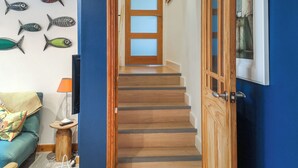 A staircase leading to a second floor with a wooden door and a blue wall. - 2 bedroom accommodation in Barnstaple (Barnstaple)