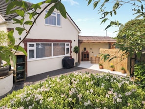 A house with a garden in front, a garage, and a small shed.