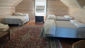 Un dormitorio abrigado en el ático con dos camas, una alfombra grande y paredes de madera.