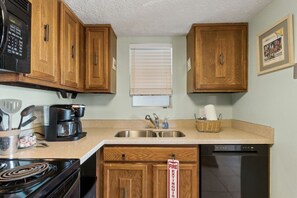 A kitchen with wooden cabinets, a microwave, a coffee maker, a sink, and a dishwasher. - New Listing - 3BR Condo w/ Pool | Walk to Beach (FERNANDINA BEACH)