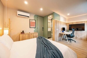 Une chambre d’hôtel moderne équipée d’un lit, d’un bureau et d’une télévision.
