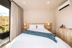 A modern bedroom with a large bed, two bedside tables with lamps, a view of a brick wall, and an air conditioning unit on the wall.