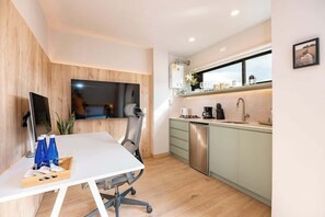 Una cocina moderna con comedor, que incluye una mesa blanca, sillas y un televisor.