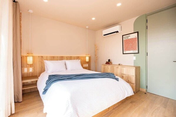 A bedroom with a bed, bedside lamps, a wardrobe, and a framed picture on the wall.