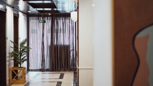Un hall d’entrée moderne avec un sol réfléchissant, une plante en pot et un panneau indiquant la sortie.