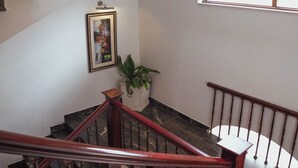 Un intérieur à plusieurs niveaux, avec un escalier en bois, un tableau encadré au mur et une plante en pot.